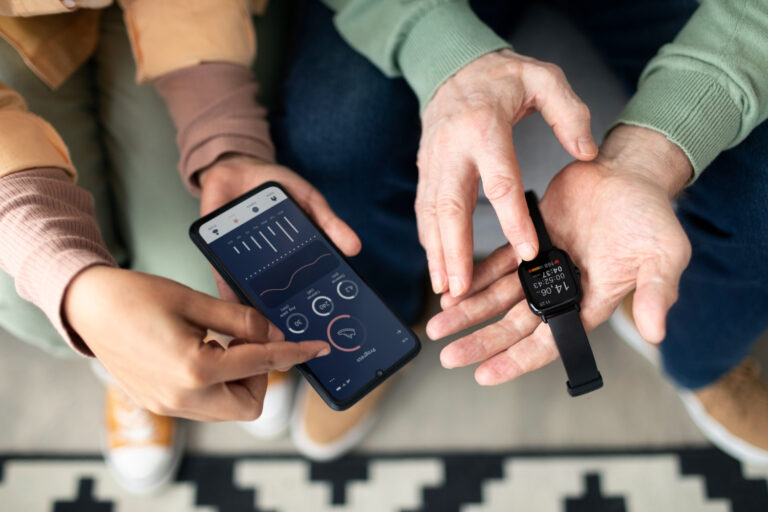 Arabic woman teaching senior man to use smartwatch with smartphone