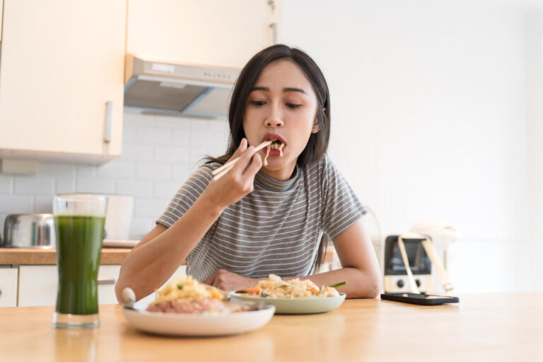 Asian girl eating thai food in kitchen counter home delivery food feeling happy