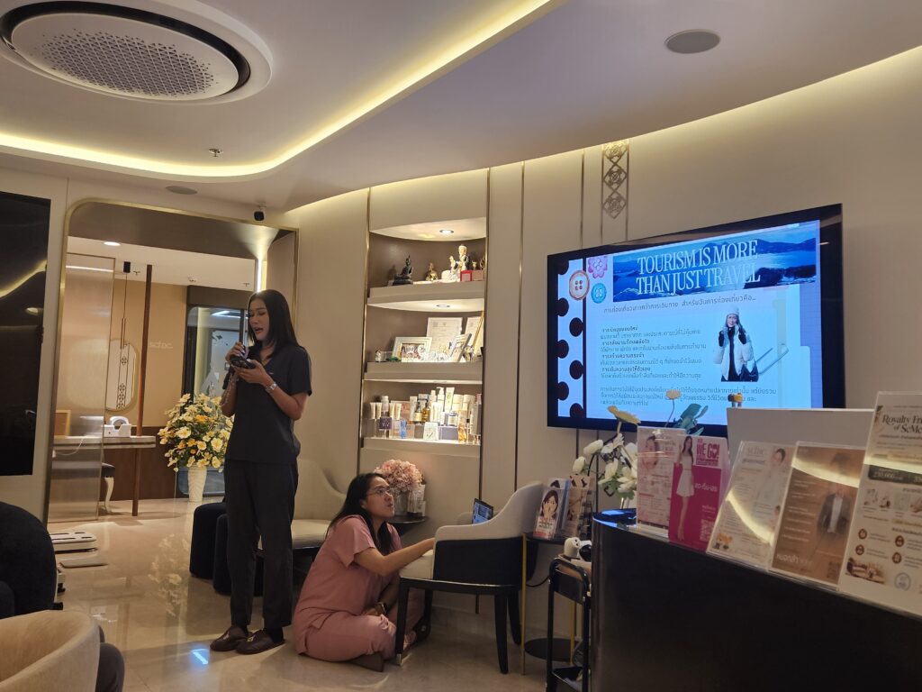 A team member presents a travel topic using a microphone beside a display.